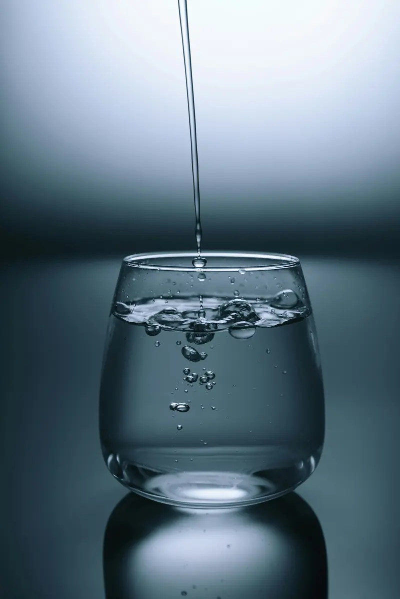 Clear water pouring into a glass, representing hydration