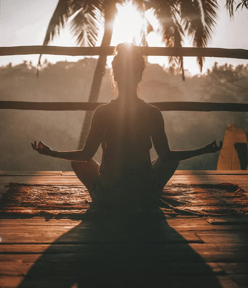 Woman meditating by the water at sunset